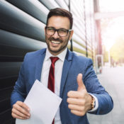 Handsome young smiling businessman giving thumbs up